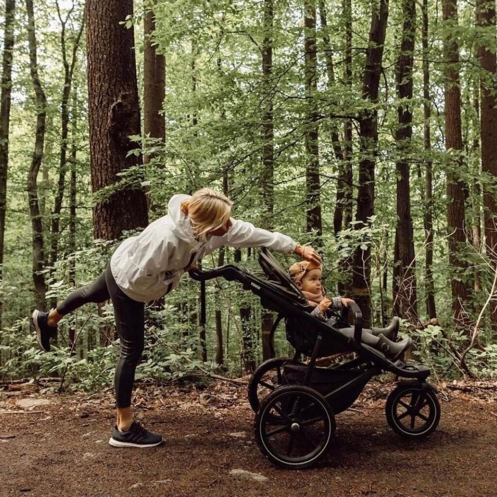 une femme poussant le poussette avec son petit dans la foret