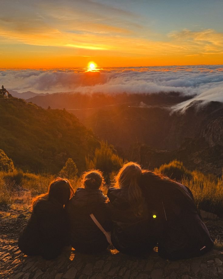 famille assis près d'une falaise regardant le levé du soleil