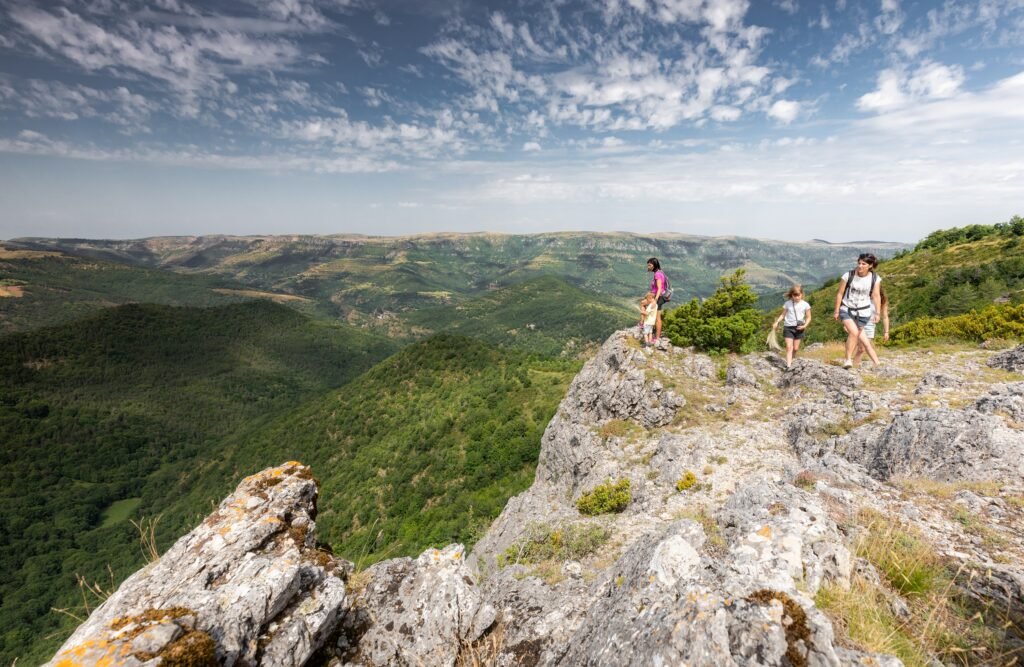 3 personnes proche de la falaise admirant la vue panoramique des cévennes